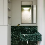 Koupelna, která zabírá nejosobnější prostor bytu. Kreativní design osvětlení, sytě zelené tóny a luxusní materiály a spousta zrcadel dodávají tomuto prostoru pocit světla a rozlehlosti. Foto: Robert Rieger