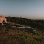 Pozemek, strmý, úzký pruh země v srdci krajiny, leží pět minut chůze od pláže a nabízí panoramatický výhled na moře, údolí a vesnici v dálce. Vévodí mu rekreační dům, který je nápadný svou minimalistickou siluetou. Foto: Clemens Poloczek