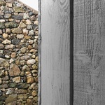 Vstupní prostor lemují stříbrně prošedlé dřevěné desky a obě křídla propojuje prosklený spojovací trakt, který poskytuje výhledy do okolí během přechodu mezi jednotlivými částmi domu. Foto: Gilbert McCarragher