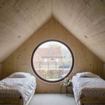 Pokojík vnoučat v podkroví je jen o spacím prostoru. Čas stejně tráví dole, s dědou a babičkou. Prostor v podstřeší prosvětluje nápadný kruhový okulus. Foto: Stijn Bollaert