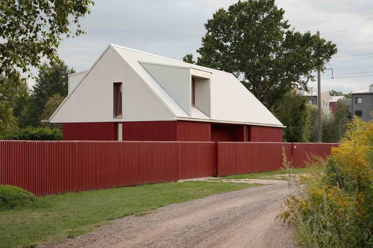 Červeně natřené dřevěné stěny a bílá střecha z vlnitého plechu tvoří základ pro „odvážný a osobitý“ exteriér House Comet. Rodinného domu v lotyšské Rize, který navrhlo místní architektonické studio Gaiss. Foto: Madara Kuplā