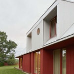 Interakce městské a venkovské scenérie jsou impulsem pro zářivě červený dům s třpytivou trojúhelníkovou střechou, s terasami a otvory, které zprostředkovávají aktivní pobyt obyvatelů vně domu. Foto: Madara Kuplā Interakce městské a venkovské scenérie jsou impulsem pro zářivě červený dům s třpytivou trojúhelníkovou střechou, s terasami a otvory, které zprostředkovávají aktivní pobyt obyvatelů vně domu. Foto: Madara Kuplā