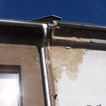 Nesprávně napojené střechy dvou objektů, nesprávně napojené žlaby – voda stéká po fasádě a degraduje zdivo římsy. (Foto: Oldřich Rejl)