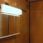 Paneláková umakartová koupelna před rekonstrukcí – detail zrcadlové skříňky s osvětlením