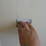Trhlina kopírující styk stěnových panelů od vibrací způsobených nevhodným způsobem provádění bouracích prací v sousedním bytě Zdroj: www.statickeposudky.cz