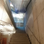Pohled na schodiště propojující vstupní prostor s garážemi a dalšími podlažími, jedná se o recyklované kamenné stupně z původní budovy. Autor: Ing. arch. Jakub Kopecký 