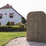 Erb stojící před domem je kamenná replika erbu Fuchsů z nedaleké zaniklé obce Bystřice (Fichtenbach), která patřila do roku 1707 k Bavorsku.  R. 1710 zde zakládá Jan Jiří Schmaus sklárnu, kterou Schmausové provozovali do r. 1765 a později převzali Fuchsové. Sklárna vyráběla korálky do růženců (tzv. páteříky) a tabulové sklo  Foto Petr Vinš